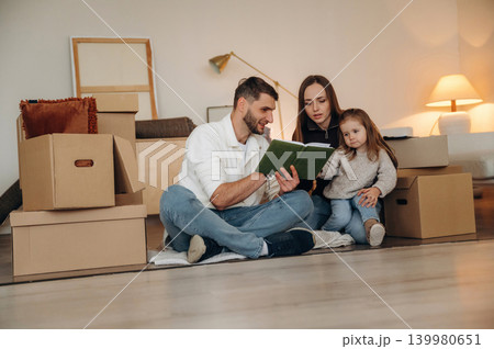 Cheerful young family with child moving into new home, standing among cardboard boxes Cheerful young family with child moving into new home, standing among cardboard boxes 139980651