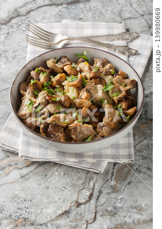 Close-up of stewed chicken gizzards with mushrooms and onions in a bowl. Vertical Close-up of stewed chicken gizzards with mushrooms and onions in a bowl. Vertical 139980669