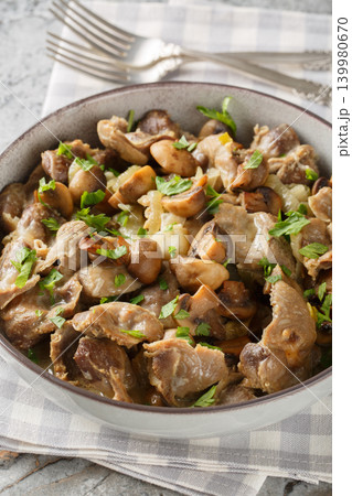 Fried chicken gizzards with mushrooms and onions close-up in a bowl. Vertical 139980670