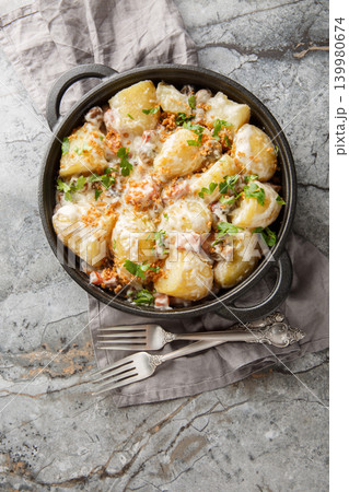 Homemade new potatoes with creamy mushroom sauce, bacon, and breadcrumbs, close-up, in a frying pan. Vertical top view Homemade new potatoes with creamy mushroom sauce, bacon, and breadcrumbs, close-up, in a frying pan. Vertical top view 139980674