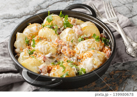Stewed new potatoes in a creamy mushroom sauce with bacon and breadcrumbs close-up in a frying pan. Horizontal 139980678