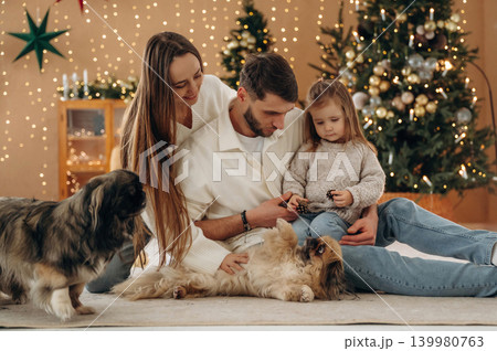 Bonding, having great time. Happy family with child and dog celebrating Christmas together at home with decorated tree Bonding, having great time. Happy family with child and dog celebrating Christmas together at home with decorated tree 139980763