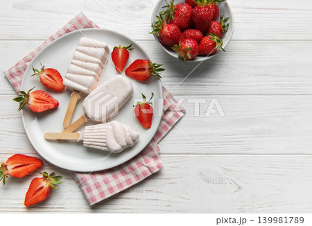 Homemade strawberry ice cream popsicles on white wood Homemade strawberry ice cream popsicles on white wood 139981789