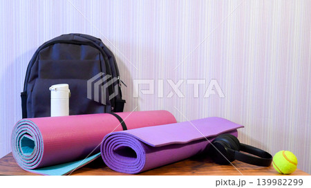 fitness equipment set with mats a backpack and headphones on a table 139982299