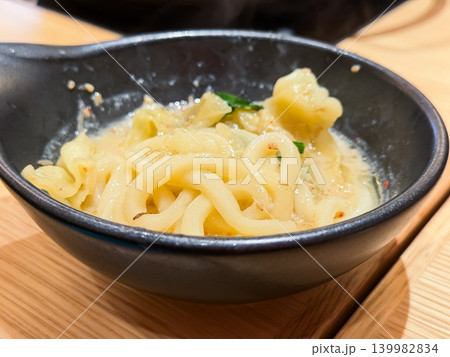 和食のもつ鍋。牛モツとニラと豆腐が具材の味噌味の鍋料理。一緒に煮込んだうどんも入れたお皿。 和食のもつ鍋。牛モツとニラと豆腐が具材の味噌味の鍋料理。一緒に煮込んだうどんも入れたお皿。 139982834