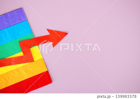 Red upward arrow lies on rainbow flag against purple background. Pink economy growth, LGBTQ market trends, queer spending power, inclusive business expansion. Red upward arrow lies on rainbow flag against purple background. Pink economy growth, LGBTQ market trends, queer spending power, inclusive business expansion. 139983378