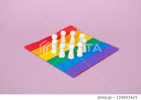 Wooden figurines arranged in circular formation on rainbow pride flag. LGBTQ rights advocacy, social justice movement, human rights protection. Wooden figurines arranged in circular formation on rainbow pride flag. LGBTQ rights advocacy, social justice movement, human rights protection. 139983425