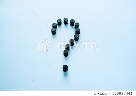 Small black barrels forming question mark on blue surface. Fluctuating oil market, petroleum resource scarcity, global inflation impact. 139983441