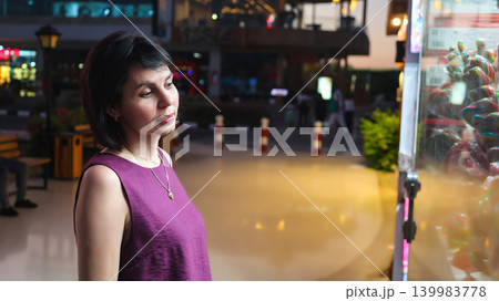 An adult woman near a store window late in the evening An adult woman near a store window late in the evening 139983778