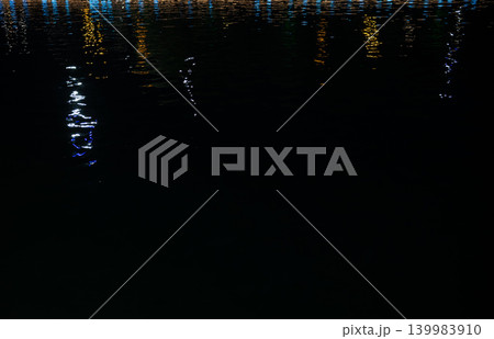 Colorful light reflections on water ripples at night, abstract neon background with copy space. 139983910