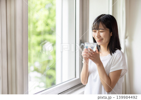 水の入ったグラスを手に窓の外を眺める日本人の若い女性 水の入ったグラスを手に窓の外を眺める日本人の若い女性 139984492