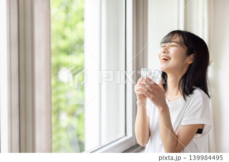 水の入ったグラスを手に窓の外を眺める日本人の若い女性 水の入ったグラスを手に窓の外を眺める日本人の若い女性 139984495
