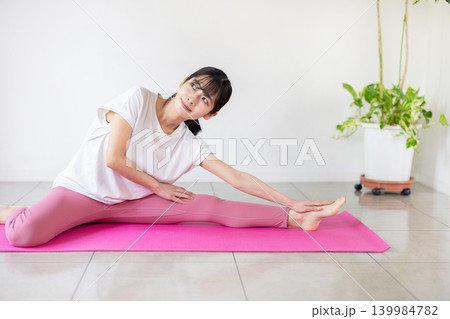 ヨガマットの上でストレッチをする日本人の若い女性 ヨガマットの上でストレッチをする日本人の若い女性 139984782
