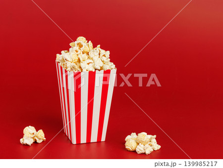 Striped popcorn box on solid red background. Minimalist food photography with copy space. 139985217