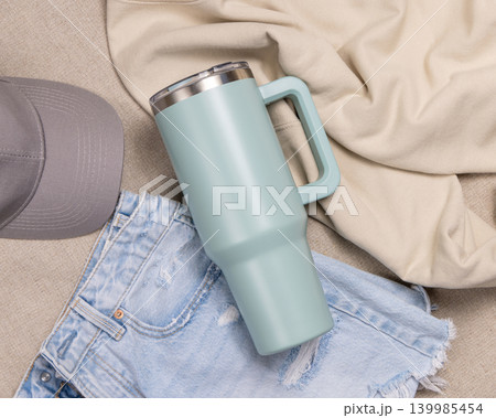 Blank sage green 40oz tumbler mockup, stainless steel travel thermos on denim and dark red sweatshirt 139985454