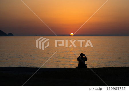 夕日の海を眺める人物シルエット 夕日の海を眺める人物シルエット 139985785