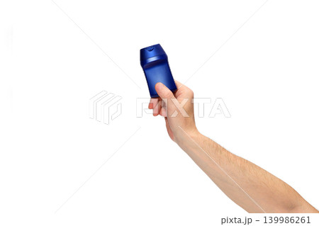 person holding a blue cosmetic bottle at an angle on a white background 139986261