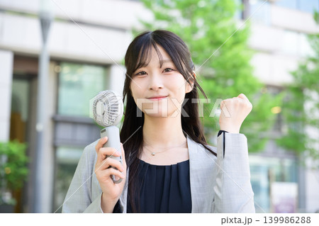 ハンディファンを持ってガッツポーズをする日本人女性 ハンディファンを持ってガッツポーズをする日本人女性 139986288