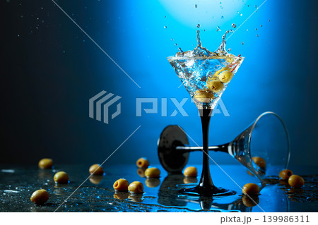 Green olives and glass of martini on a black stone table. 139986311