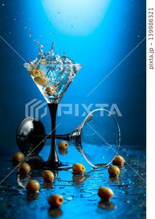 Green olives and glass of martini on a black stone table. Green olives and glass of martini on a black stone table. 139986321