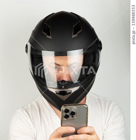 Man in black motorcycle helmet takes selfie with smartphone in hand 139986553