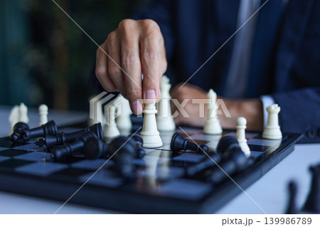 Businessman wearing suit, playing chess, game of strategy, leadership and management concept. Businessman wearing suit, playing chess, game of strategy, leadership and management concept. 139986789