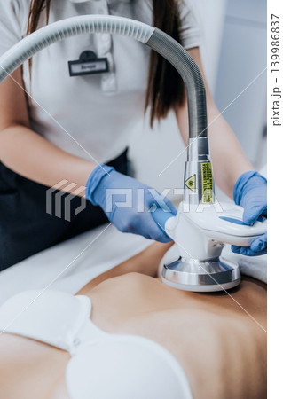 Close-up of a young woman receiving professional body contouring massage treatment for slimming and cellulite reduction in a beauty clinic. Non-invasive aesthetic procedure, skincare, body care Close-up of a young woman receiving professional body contouring massage treatment for slimming and cellulite reduction in a beauty clinic. Non-invasive aesthetic procedure, skincare, body care 139986837