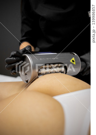 Close-up of a young woman receiving professional body contouring massage treatment for slimming and cellulite reduction in a beauty clinic. Non-invasive aesthetic procedure, skincare, body care Close-up of a young woman receiving professional body contouring massage treatment for slimming and cellulite reduction in a beauty clinic. Non-invasive aesthetic procedure, skincare, body care 139986857