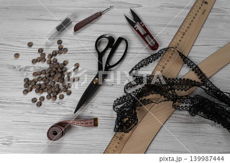 Collection of sewing tools and tailoring accessories including scissors, measuring tape, ruler, threads and buttons arranged on table. Concept of handmade craft, tailoring, fashion design and 139987444