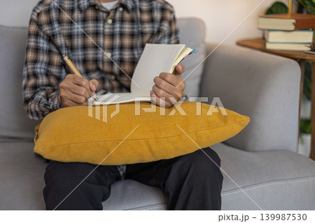 Person journaling for mental health and mindfulness sitting on a sofa. 139987530