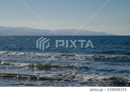 Soft waves caress the shore under a bright blue sky during a tranquil seaside Soft waves caress the shore under a bright blue sky during a tranquil seaside 139988155