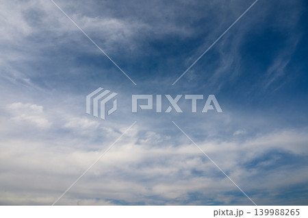 Vibrant cloud patterns dancing across a vast blue sky at midday under soft sunlight Vibrant cloud patterns dancing across a vast blue sky at midday under soft sunlight 139988265
