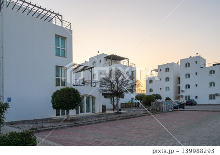 Sunset paints serene white buildings in a quiet residential area 139988293