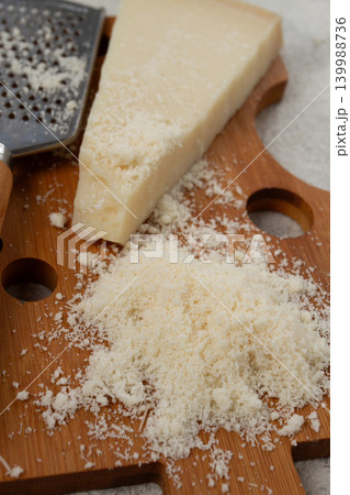 Freshly sliced and grated cheese, parmesan cheese, on a wooden chopping board, rustic style, no people 139988736