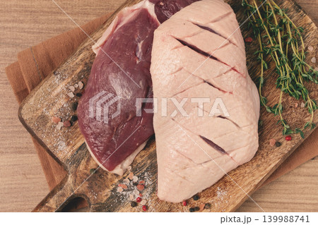 Fresh raw duck breasts, on a wooden chopping board, with herbs and spices, no people Fresh raw duck breasts, on a wooden chopping board, with herbs and spices, no people 139988741