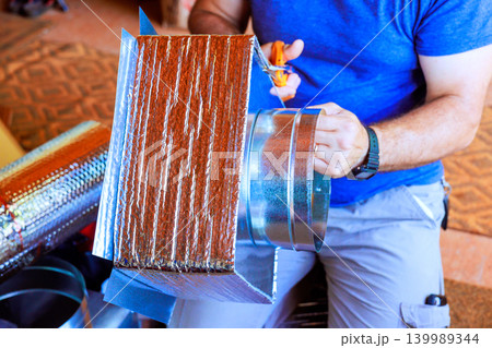 Carpenter is cutting metal ducting in workshop tools, materials are spread out around them. Carpenter is cutting metal ducting in workshop tools, materials are spread out around them. 139989344