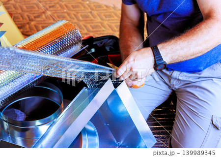 Handyman is using tape to secure metal parts for project inside building during HVAC repair Handyman is using tape to secure metal parts for project inside building during HVAC repair 139989345