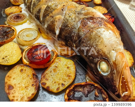 Delicious roasted fish with colorful vegetables on a sunny kitchen table 139989396