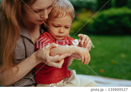 Mother puts cream on baby's hand in summer 139989527