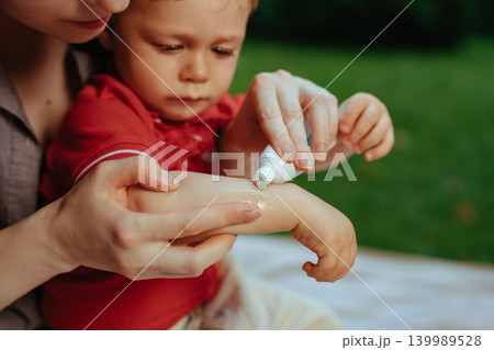Mother puts cream on baby's hand in summer Mother puts cream on baby's hand in summer 139989528