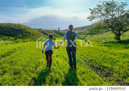 Mother and son walking in the field holding hands Mother and son walking in the field holding hands 139989542