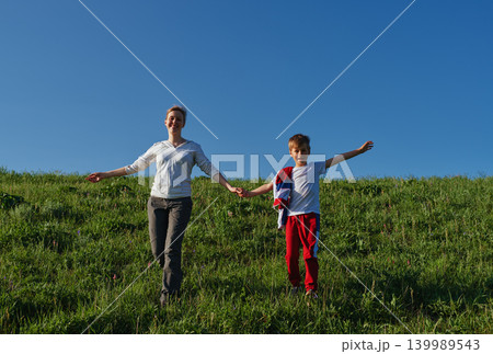 Happy mother and son walking in the field holding hands 139989543