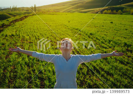 Young happy woman delighting good weather on green field 139989573