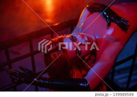 Portrait of sexy woman in red latex dress on metallic cage Portrait of sexy woman in red latex dress on metallic cage 139989589