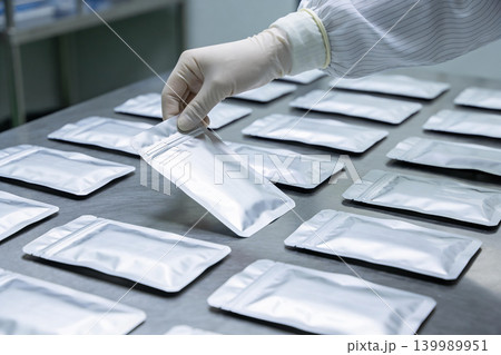 Gloved hand selecting a sealed foil pouch from a tray of many Gloved hand selecting a sealed foil pouch from a tray of many 139989951