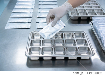 Gloved hand placing a sealed pouch into a compartmentalized tray for laboratory testing Gloved hand placing a sealed pouch into a compartmentalized tray for laboratory testing 139990093
