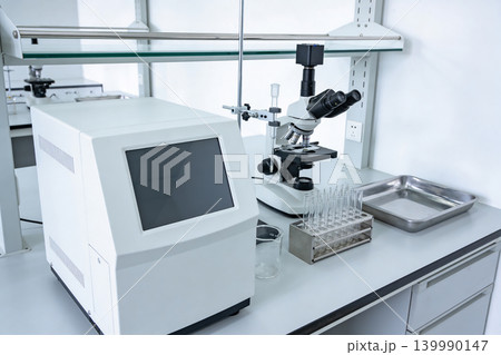 Modern laboratory equipment with microscope and testing devices on a clean white countertop 139990147
