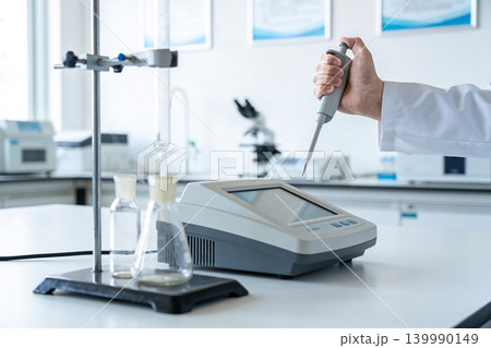 Scientist using a pipette in a modern laboratory with scientific equipment 139990149