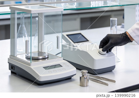 Precision laboratory scales and scientific equipment on a clean white table 139990216