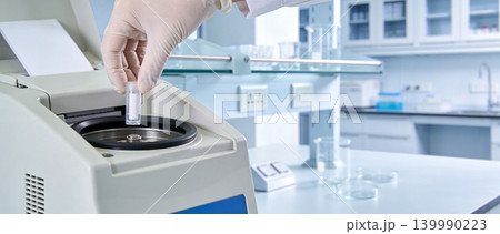 Scientist places sample tube into laboratory centrifuge for analysis Scientist places sample tube into laboratory centrifuge for analysis 139990223